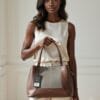 A model holding our Women's structured handbag in coffee brown with herringbone textile panel and dual top handles — shop Pedra bags at Nansey Emporium Ghana